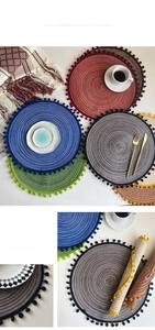 Close-up of colorful round woven placemats with soft pom-pom edges in a home setting