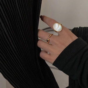 Detail of minimalist gold-plated ring set featuring a large oval white mother of pearl inlay