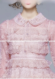 Détails de broderie sur le col Claudine d'une robe en dentelle rose aux motifs floraux