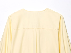 Close-up of the pale yellow poplin shirt back featuring pleated detail and stitching