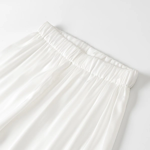 Détail du pantalon en satin blanc avec taille élastique et texture plissée lisse