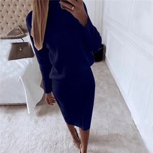 Detail of dark blue knit set showing high collar sweater and skirt in a bedroom setting