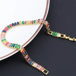 Detailed shot of multi-colored zircon stones on a gold-plated bracelet on a white ceramic plate