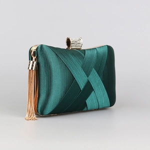 Detail of dark green satin evening clutch with gold tassels and rhinestone clasp
