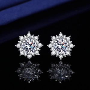 Macro shot of silver snowflake stud earrings featuring round cut stones on silk