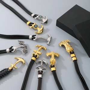 Close-up of vintage Mjolnir and nautical anchor pendants with braided leather cords