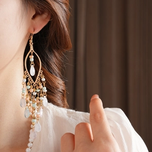 Macro shot of Bohemian layered beaded tassel earrings with droplets on female model