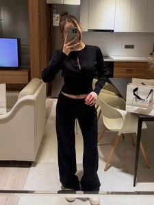 Detail view of black slim knit cardigan and high-waist wide-leg pants set in mirror selfie