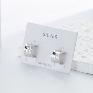 Detail of s925 silver C-shaped earrings with hammered texture on a white display card