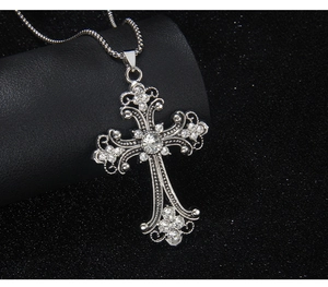 Detailed close-up of a silver vintage cross pendant set with sparkling rhinestones