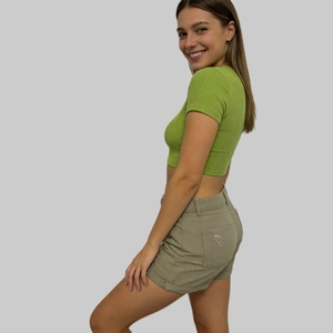 Dettaglio degli shorts di jeans oliva a vita alta con risvolto ed effetto consumato