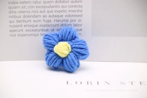 Macro shot of handcrafted blue milk cotton crochet flower with yellow center on white paper