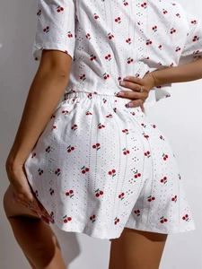 Detailansicht des weißen Pyjama-Sets mit Kirschmuster und hohler floraler Spitzenstruktur
