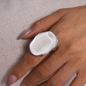 Close-up of a large oval white resin stone ring on a model hand with silver band