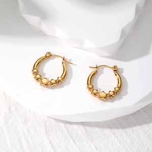 Detailed close-up of golden geometric earrings with star charms on a white display