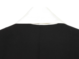 Détail du col d'un blazer noir avec revers en satin blanc et finitions de couture