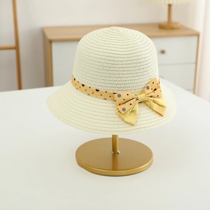 Detailed texture of beige straw sun hat featuring yellow polka dot ribbon and bow accent