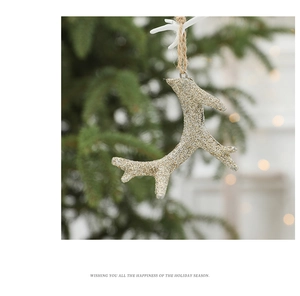 Golden glitter reindeer antler ornament hanging on a Christmas tree with bokeh lights