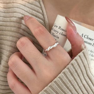 Detailed view of silver braided twisted rope ring on model hand with elegant knit background