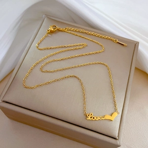 Close-up of golden stainless steel Love heart necklace on a beige jewelry box cover