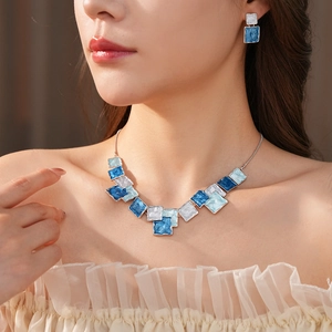 Detail of silver geometric square necklace and earrings set with blue enamel inlay