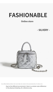 Detail of silver quilted chain bag featuring a gold ball charm and metallic finish