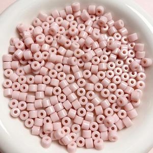 Vista macro di perline acriliche rosa cilindriche da 6 mm per gioielli in una ciotola
