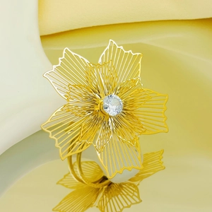 Close-up of golden hollow flower ring with sparkling zircon center on yellow background