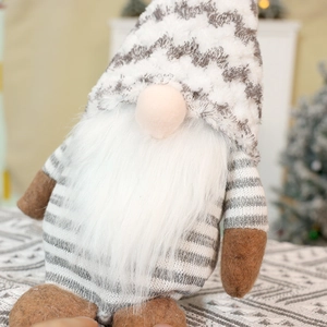 Close-up of Christmas gnome plush toy with knitted hat and soft beard on festive background