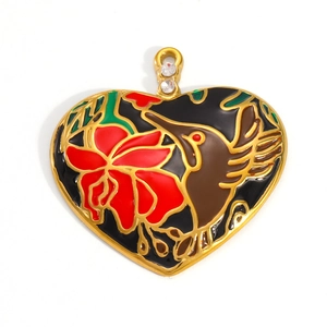Macro detail of heart-shaped enamel pendant featuring a hummingbird and red flower on gold plating