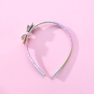 Rainbow sequin children's headband with cute bow detail on a solid pink background