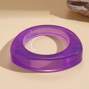 Detail of purple translucent resin bangle with glitter texture on stone background