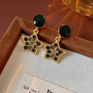 Vue macro de boucles d'oreilles étoile dorées avec strass noirs sur velours