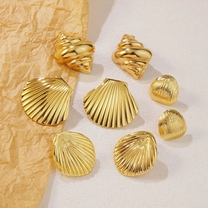Golden stainless steel ocean shell and starfish stud earrings set on a textured background