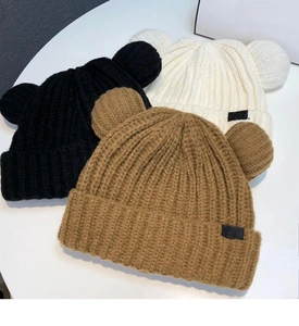 Détail de la texture tricotée de bonnets d'hiver avec oreilles d'ours en noir blanc et brun