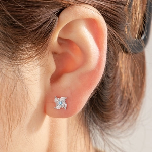 Sparkling zircon windmill stud earring with a blue center stone on female model ear