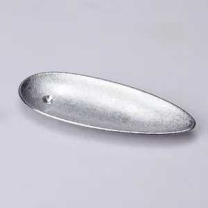 Macro detail of silver boat-shaped metal incense burner with sandblasted matte texture