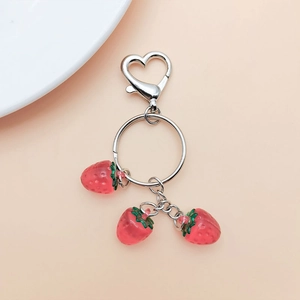 Detailed view of red strawberry pendants with silver heart clasp and key ring