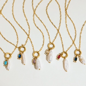 Golden necklaces with baroque pearls and colorful gemstones on a white background