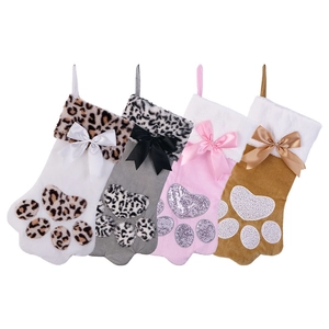 Macro shot of four plush Christmas stockings in paw shapes with festive bows and sequins