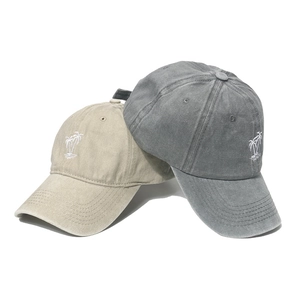 Detail of washed cotton baseball caps in khaki and dark grey with palm tree embroidery