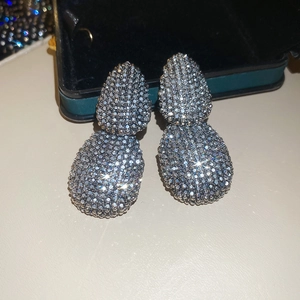Macro shot of silver teardrop earrings with white zircon pavé on green velvet box