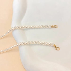 Elegant white faux pearl necklace with gold stainless steel clasp on a minimalist display