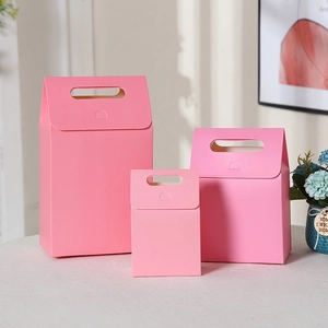 Detailed view of pink kraft paper gift bags in three different sizes with handles