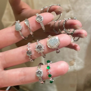 Detail showing stacked zircon and resin rings with green gemstones on silver metal bands