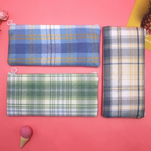 Flat lay view of three canvas plaid pencil cases in blue, green and beige on pink backdrop
