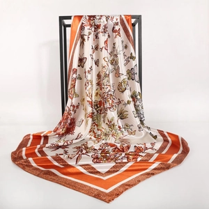 Detail of silk satin scarf showing orange borders and butterfly floral print on cream base