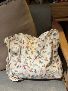 Detailed view of cream canvas tote bag featuring various cartoon dog prints on a sofa
