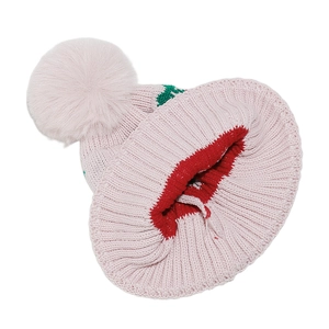 Detail of pink knitted girl's hat featuring plush pom-pom and festive knit patterns