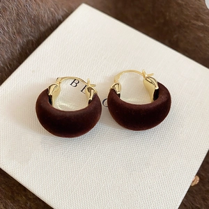 Detail view of gold hoop earrings with brown flocking texture on textured display card